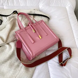 Pink square leather handbag with dual handles and a trendy wide crossbody strap