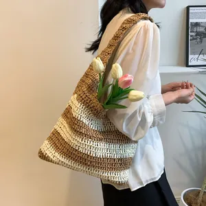 Close-up of a striped woven straw tote bag with wide shoulder strap for beach holidays