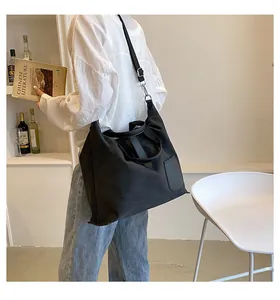 Close-up of the black canvas tote bag showing the leather pocket and adjustable shoulder strap