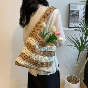 Chic striped straw tote bag worn over the shoulder for a trendy summer beach look