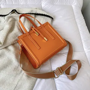 Chic orange square crossbody bag with dual handles and wide woven shoulder strap