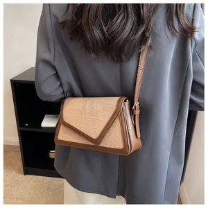 Détail du rabat motif crocodile et bandoulière en cuir marron d'un sac bicolore chic