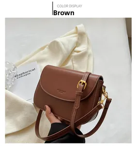 Detail of a vintage brown leather crossbody bag with logo embossing and gold hardware