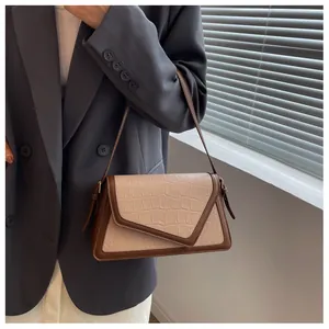 Détail d'un sac à bandoulière beige à motif crocodile avec rabat en V et bords bruns