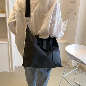 Minimalist black canvas tote bag with leather pocket shown from a back view