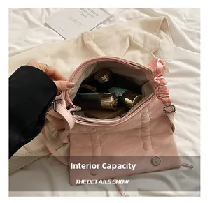 Détail de l'intérieur spacieux avec fermoir magnétique et foulard floral sur le sac rose