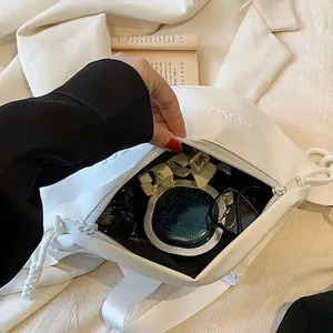 Sac bandoulière blanc en similicuir avec chaîne montrant un intérieur spacieux pour objets