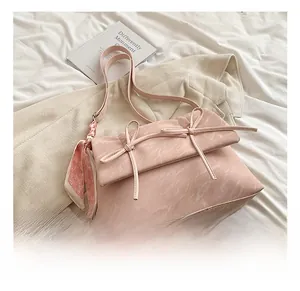 Détail de la texture marbrée du sac à main rose clair avec nœud décoratif et foulard