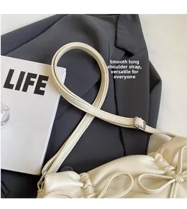 Detail of cream white leather bag with adjustable long shoulder strap and silver buckle