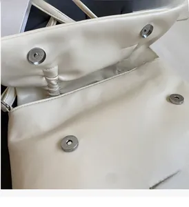 Detail of cream leather bag featuring silver magnetic clasps and logo plaque