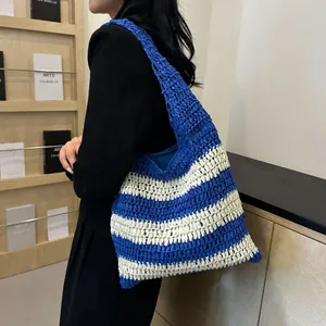 Detail view of woven blue and white striped tote bag with rich knit texture on model