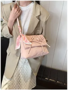Détail du sac à bandoulière rose avec nœuds et accessoire élégant en foulard de soie
