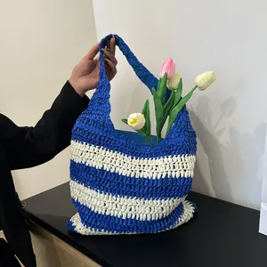 Detail of blue and white striped straw tote bag featuring woven texture and floral decor