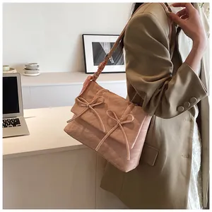 Sac bandoulière rose avec nœuds et détail de foulard porté sur l'épaule
