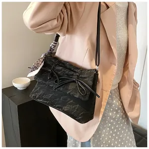 Détail du sac cabas plissé noir avec nœud élégant et foulard en soie à motif cœurs