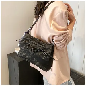 Détail du sac à bandoulière noir avec nœud, tissu texturé et accent en foulard de soie