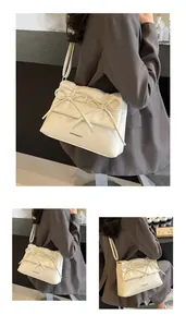 Detail of the elegant cream shoulder bag featuring decorative bows and pleated design