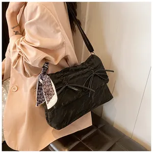 Détail du sac cabas noir texturé avec nœuds décoratifs et foulard en soie à cœurs