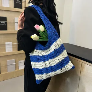 Detail of blue and white striped straw tote bag featuring a woven texture and tulips