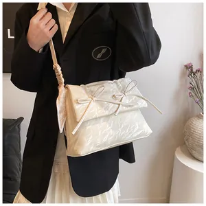Détail du sac à main crème à nœuds avec texture plissée et foulard à motif cœurs