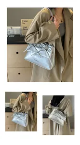 Detail of silver metallic shoulder bag with double bow ties and embossed logo finish