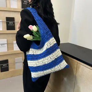 Detail showing blue and white striped woven texture on a large crochet straw tote bag