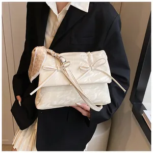 Détail du sac beige à nœuds avec texture marbrée et foulard en soie à cœurs