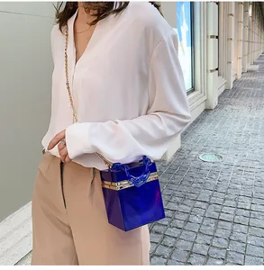 Detail of blue acrylic box bag with chunky chain strap and gold metal shoulder chain