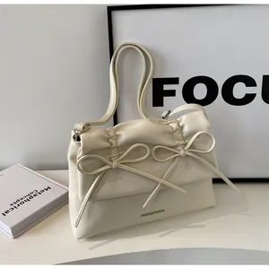 Detail of cream white shoulder bag featuring delicate pleated bows and metallic logo