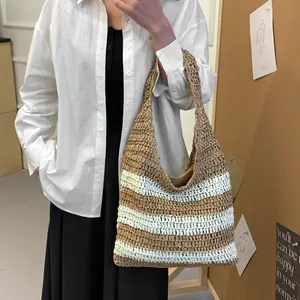 Brown and white striped straw tote bag worn over the shoulder for beach vacations
