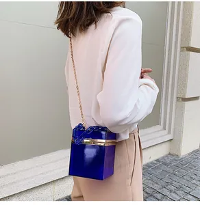 Detail of royal blue acrylic box bag with chunky chain strap worn by a model