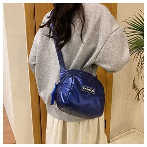 Detail of blue puffer crossbody bag showing quilted fabric texture and Fashion label