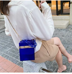Detail of blue acrylic cube handbag with gold metal frame and thick chain strap