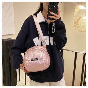 Detail view of metallic pink quilted shoulder bag with wide strap and fashion label