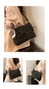 Détail du sac noir à nœuds avec un foulard en soie à motif cœur sur la bandoulière