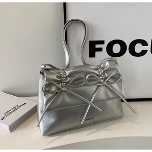 Detail of silver metallic wrinkled tote bag featuring double bow accents and a high-gloss finish