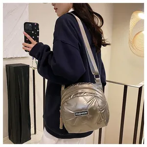Detail of champagne gold quilted puffer crossbody bag with FASHION label and strap