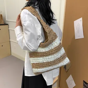 Detail of striped straw tote bag on shoulder showing large capacity and woven texture