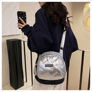 Detail of silver quilted puffer crossbody bag with FASHION label and woven strap charm