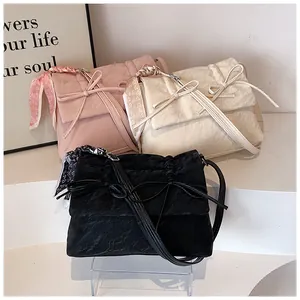 Détail de sacs à main à nœud papillon en rose, crème et noir avec texture plissée