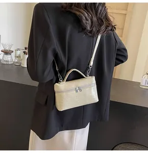Dettaglio mini borsa a mano beige con stampa coccodrillo e cerniera in metallo