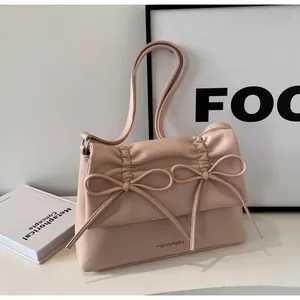 Detail of soft pink faux leather bag featuring pleated texture and twin bow accents