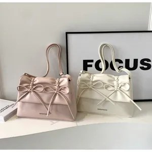 Detail of the chic pleated flap and twin bows on pastel pink and white leather bags