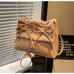 Close-up of pink ruched shoulder bag with bow details and metallic brand logo