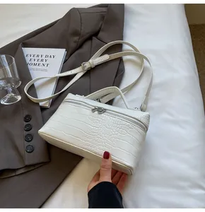 Dettaglio della borsa bianca con motivo a coccodrillo, zip argentata e tracolla sottile