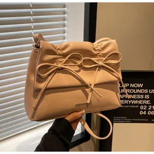 Detail showing the soft pleat texture and decorative bows on the stylish pink crossbody bag