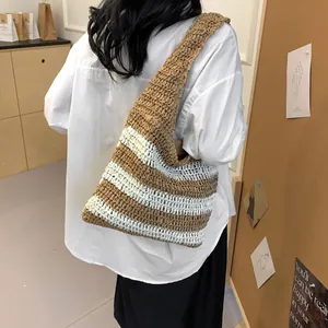 Large striped straw tote bag shown worn by a model for vacation beach style
