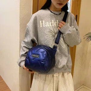 Glossy bright blue quilted puffer crossbody bag with fashion tag on a female model