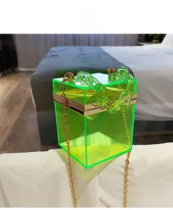 Detailed view of neon green acrylic box bag with chunky chain and gold metal strap