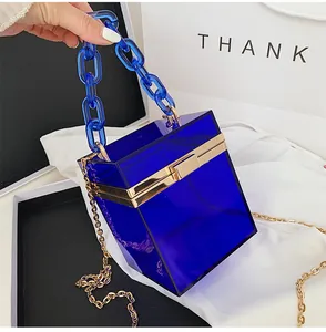 Detail of royal blue acrylic box bag with gold metal frame and transparent chain strap
